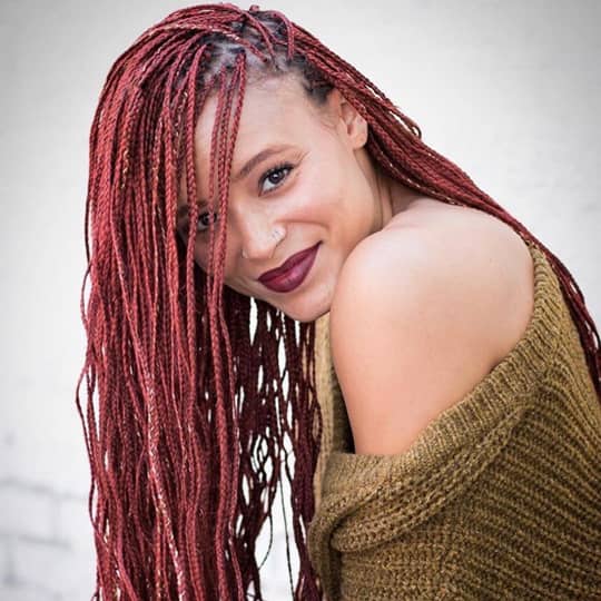 Mujer sonriente con trenzas largas de color vinotinto vistas de frente