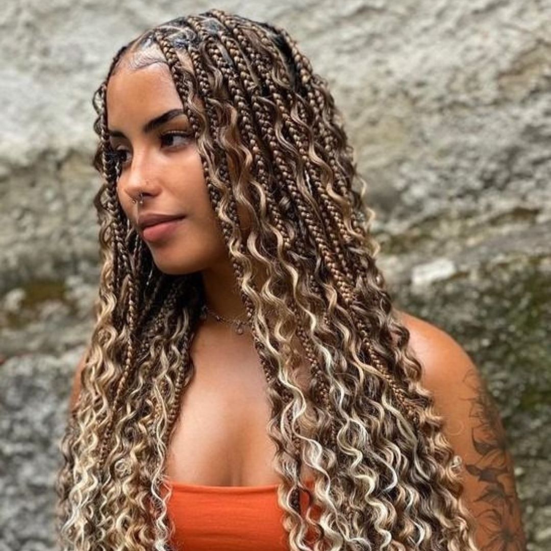 Mujer con trenzas bohemias y rizos sueltos en tonos miel